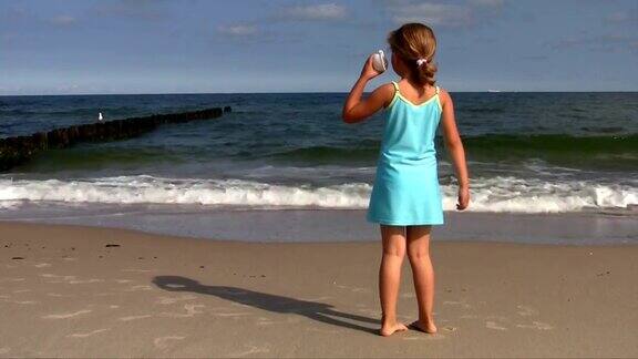 带着贝壳的小女孩在海滩上