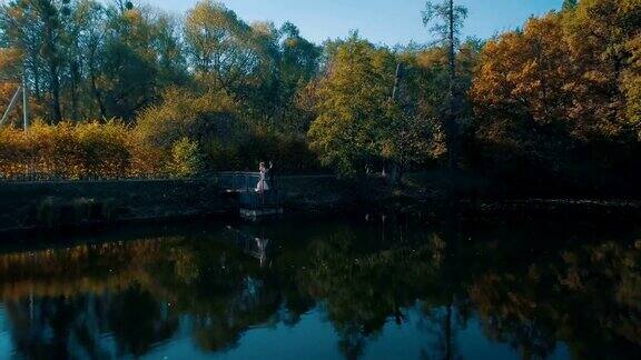 一对年轻的夫妇站在美丽的湖边的一座小桥上