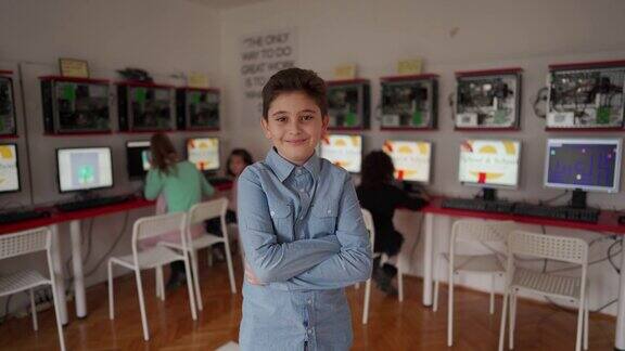 可爱的男孩站在现代计算机学校的教室里