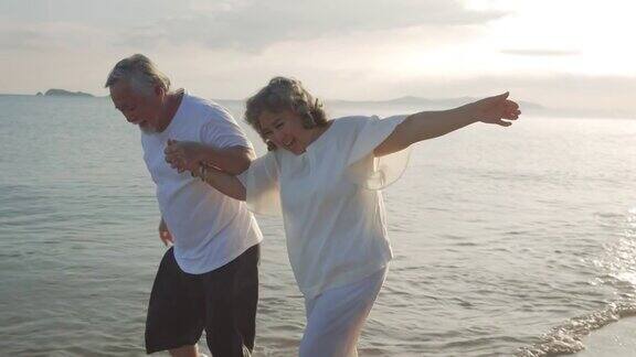 幸福亚洲夫妇老年退休在日落海滩休息和跑步蜜月家庭一起人的生活方式慢镜头
