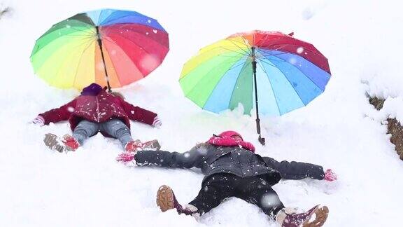 小女孩们在雪地里用手做雪天使玩耍