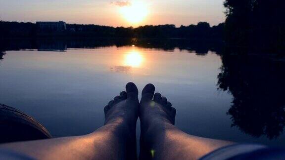 脚躺在湖边池塘附近的码头上