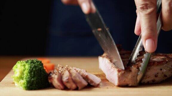 厨师的手在厨房的棕色木板上用刀把牛排切成小块