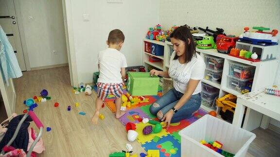 小男孩帮助妈妈清理房间的玩具