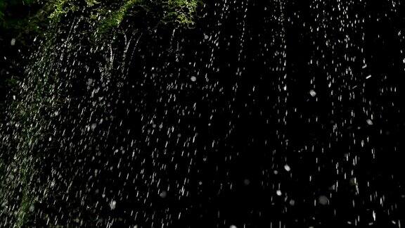 慢镜头瀑布在山上高速卷特写的春天的水滴下落和溅在绿色的苔藓
