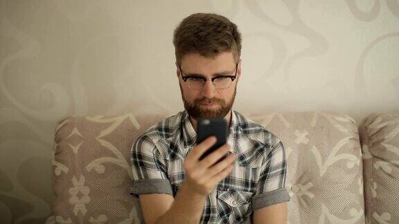 戴眼镜的大胡子男子在家里使用智能手机