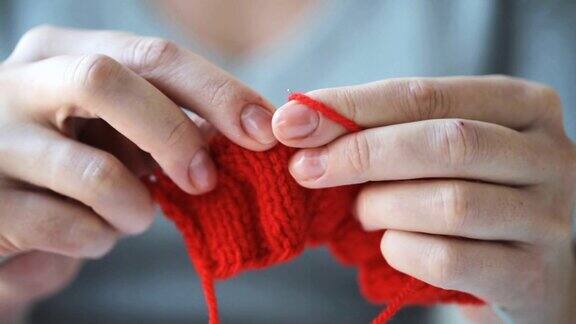 用针和红毛线编织的女人