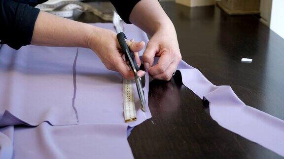 裁缝用剪刀按照粉笔标记的图案裁剪布料特写手
