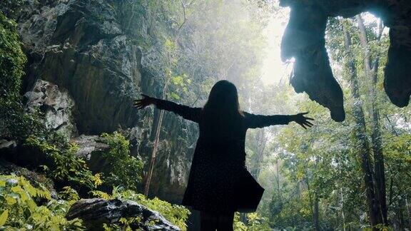 女人站在悬崖前在雨天的剪影举起她的手向天空