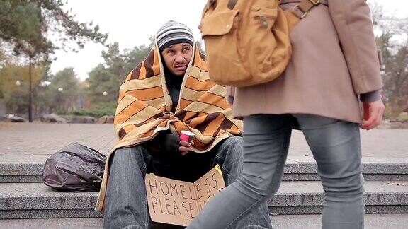 善良的年轻女人把钱给在街上乞讨的无家可归的穷人