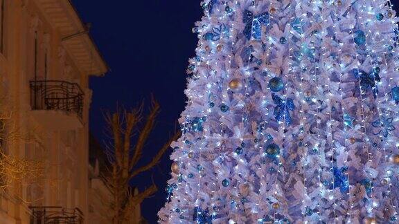 在夜晚的城市街道上白色的圣诞树被圣诞灯点亮