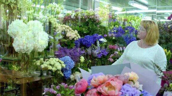 成熟的女人在花店挑选鲜花