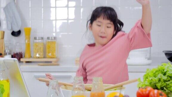 健康饮食快乐的孩子女孩跳舞和准备蔬菜沙拉在厨房日本家庭