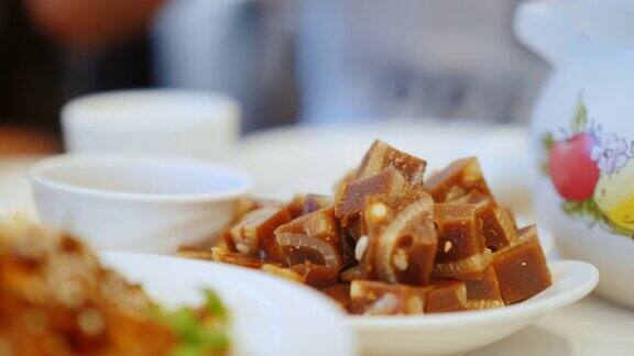 用筷子夹一道传统的中国菜特写-肉冻的方块中餐厅与食物概念