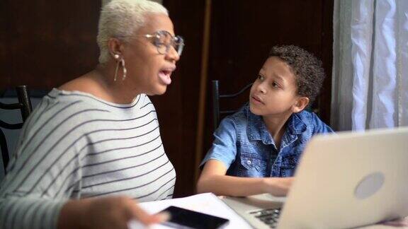 母亲和儿子在家里用笔记本电脑在线学习