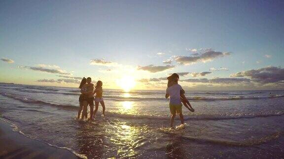 日出时分一群朋友在美丽的海滩上奔向大海