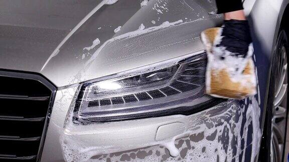 一个男人在洗汽车前灯手动洗车