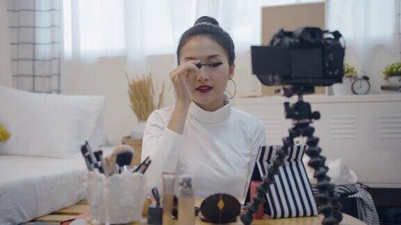 年轻的亚洲女性美网博主录制视频与化妆品