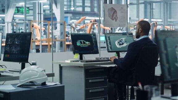 汽车工厂办公室:黑色工程师工作在桌面电脑屏幕显示CAD软件与3D涡轮发动机电动汽车制造高科技车辆的自动化机器人手臂装配线