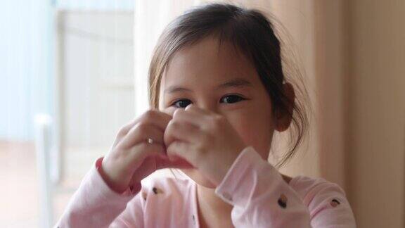 4K慢动作的快乐小混血亚洲女孩用她的手盖住她的眼睛做心形手势捐赠慈善关心爱心脏健康社会距离概念
