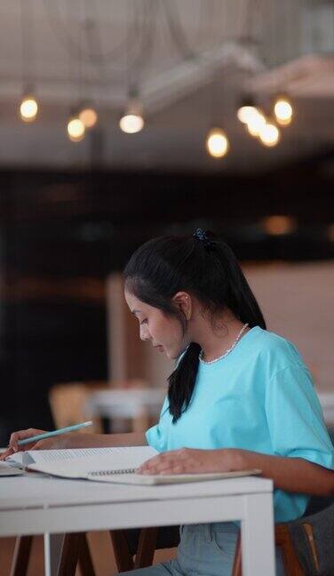 亚洲女学生在笔记本电脑上写同时使用笔记本电脑在学校图书馆学习做作业