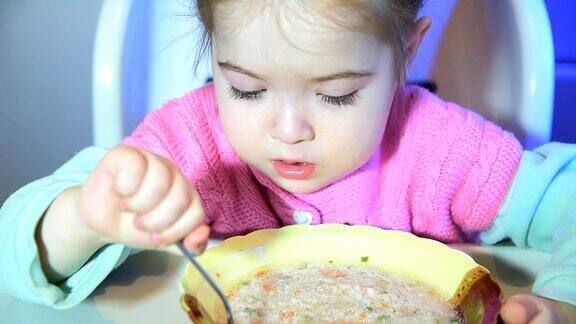 小女孩正在用盘子喝汤