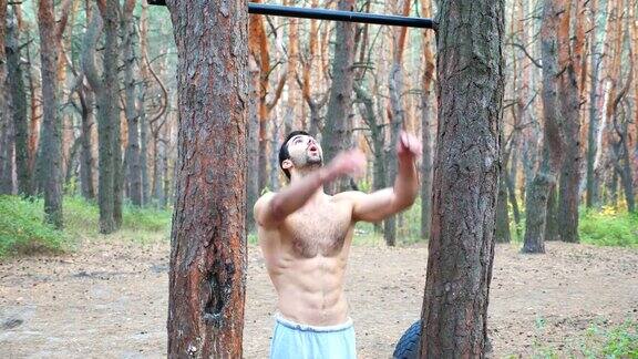 运动员站在自然环境中的肖像肌肉男看着镜头开始在单杠上训练运动员在森林中进行力量训练积极的生活方式