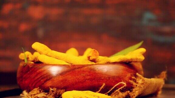 整个姜黄手指或棍子在一个碗与绿叶在木制背景黑暗的主题干姜黄姜黄或halkund旋转