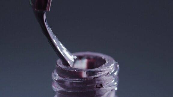刷子正在从瓶子里取紫色指甲油极端特写镜头