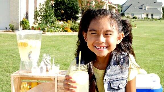 可爱的亚洲小女孩在柠檬水摊位前微笑