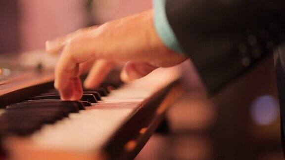 音乐家在键盘上弹奏合成器的钢琴键音乐家在音乐会舞台上演奏乐器穿黑衣的男人在夜总会表演爵士乐、灵魂乐和休闲歌曲轻松的气氛