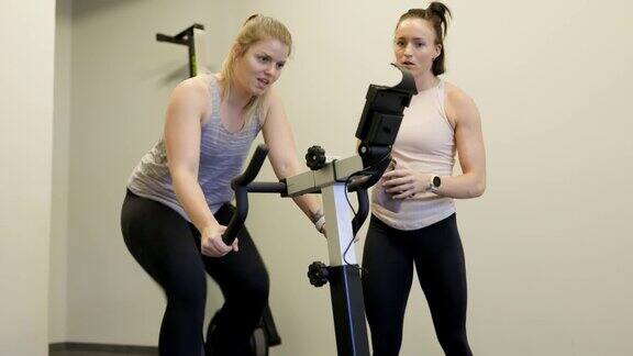女教练激励一个在固定自行车上锻炼的女人