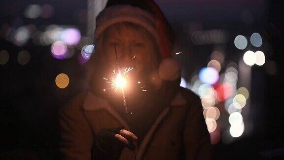 微笑的年轻女子拿着新年的烟火在黑暗的背景