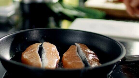手把一块红色的鱼片放在热锅上的特写
