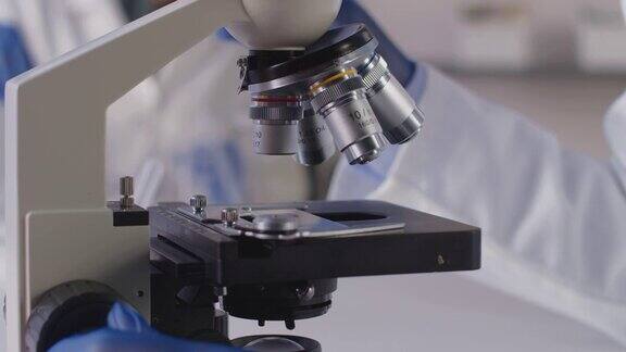 女性实验室工作人员或抽血师在实验室用显微镜分析血样的特写