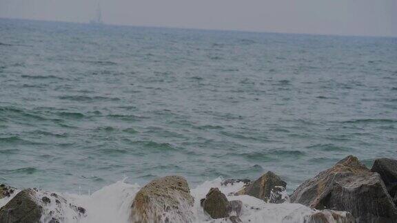 大浪冲击着海岸岩石背景是船只