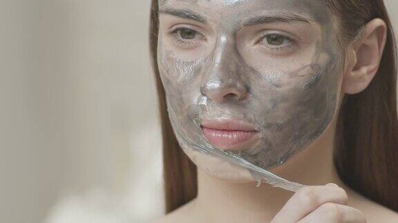 特写的一个女孩的头从她的脸上摘下化妆面具