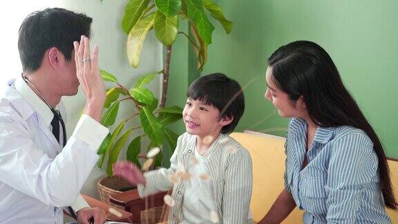 快乐健康的亚洲可爱的小男孩给亚洲男医生儿科医生在办公室诊所击掌亚洲男性儿科医生手持听诊器检查心脏医疗保健