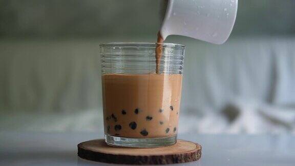 在玻璃杯中倒入加珍珠泡的泰国奶茶慢动作