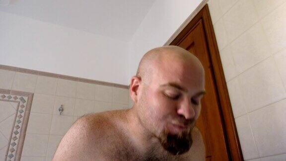 秃头男人在浴室里用电动牙刷刷牙