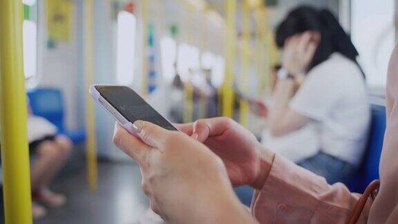 在公共交通工具中使用手机的女性的手靠近