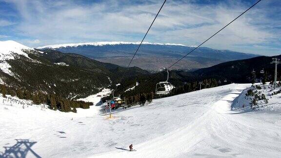 在保加利亚班斯科的托姆巴世界杯滑雪道顶端搭载滑雪者和单板滑雪者的滑雪缆车背景是班德里察