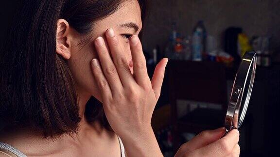 视频的年轻亚洲妇女使用化妆品痤疮霜在她的脸上治疗痤疮问题