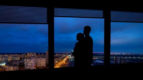 这个男人和女人站在有城市景观的窗户旁边时间流逝