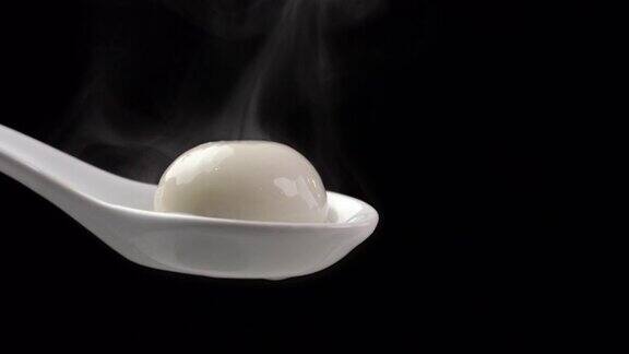 汤圆汤圆汤圆用滚烫的蒸汽在一个白色的勺子在黑色的背景
