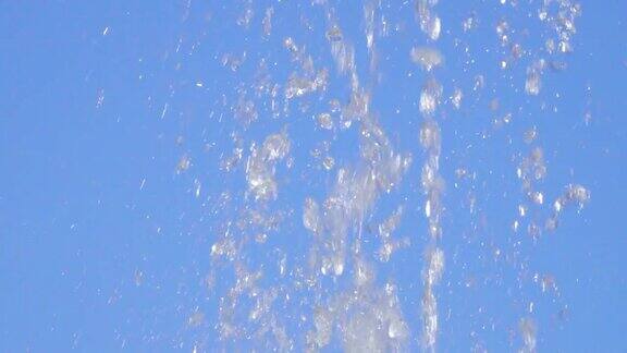 在天空的背景上喷水阳光下喷泉水滴的特写