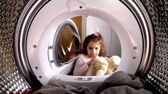 小女孩把她的毛绒玩具装到洗衣机里
