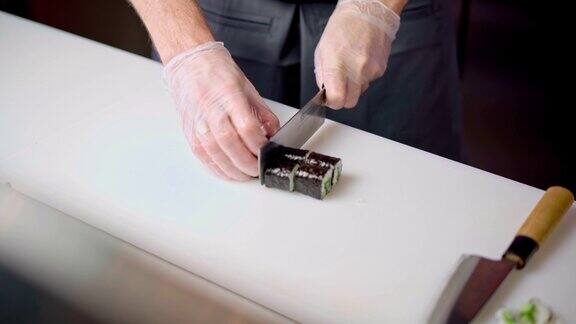 男厨师在餐厅厨房用手切割准备好的寿司卷