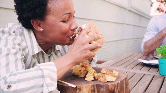 一个非洲裔中年妇女在餐厅吃汉堡的照片