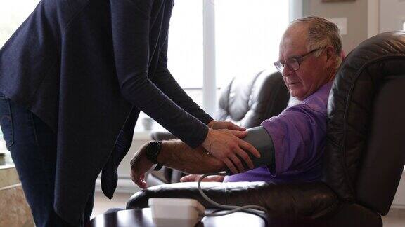 护士在家为一位老人检查血压